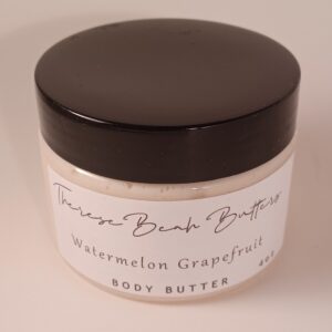 Clear jar with black lid. ThereseBeah Butters logo in fancy script. Watermelon Grapefruit Shea butter written in script detailing fragrance. 4 ounce product content. Butter is an ivory color.